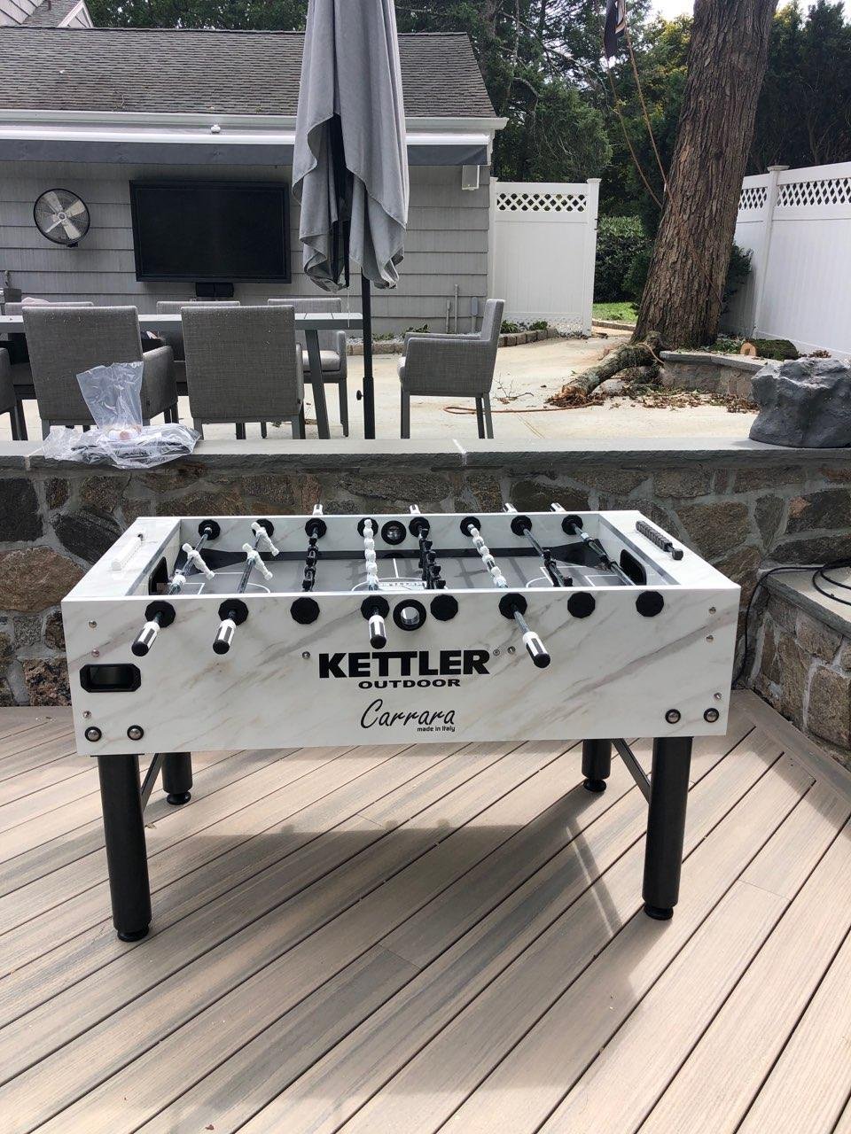 Kettler Carrara weatherproof outdoor foosball table on a backyard deck, free cover included.