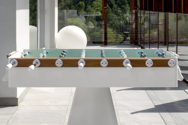 Kettler FAS Ciclope White Foosball Table on sunlit patio with glass railings and white handles.