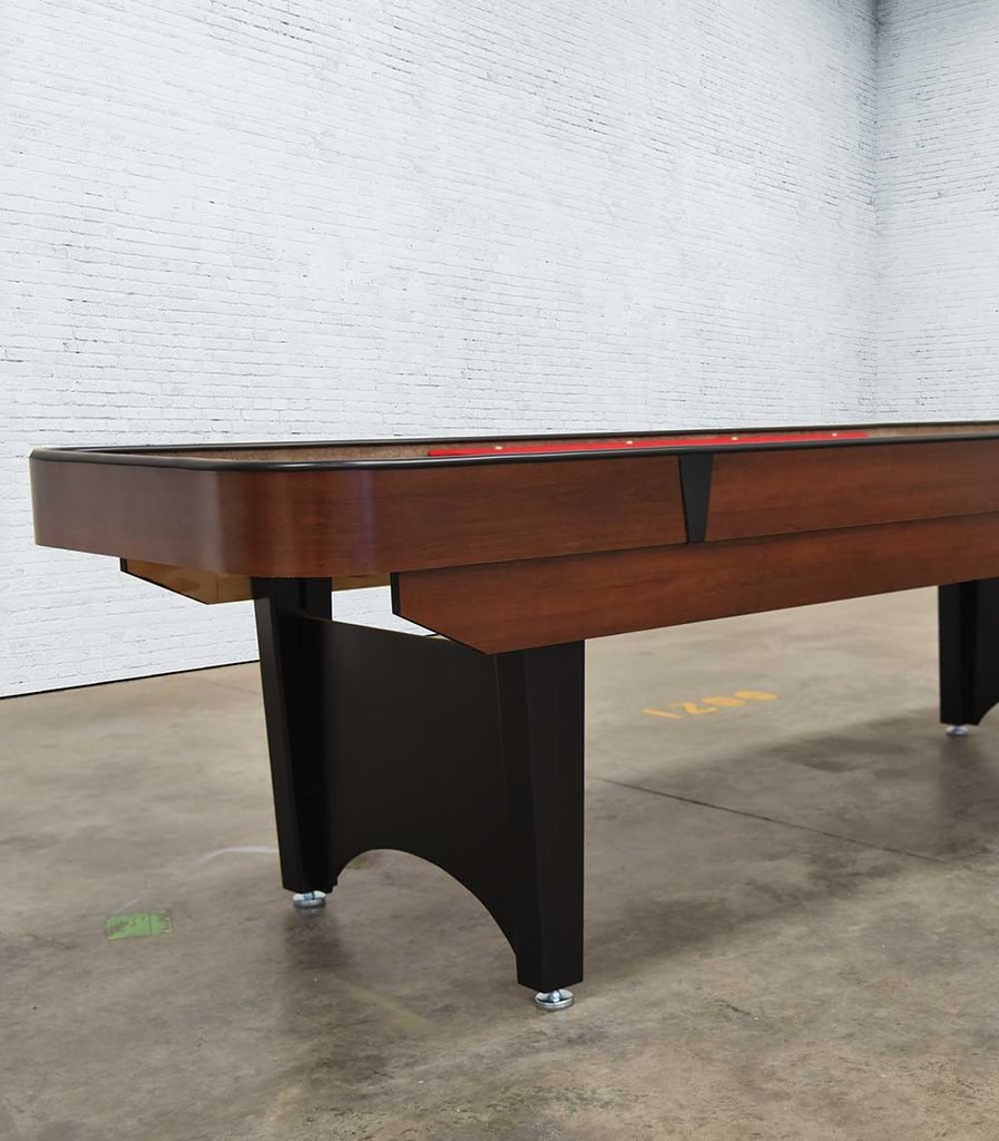A Venture Classic Bank Shot 9' Shuffleboard Table with black legs stands by a white wall.