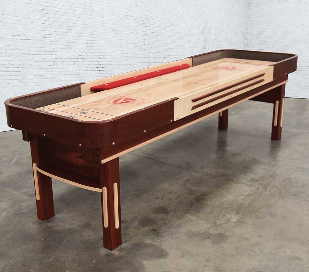 A Venture Grand Deluxe Bank Shot 9' Shuffleboard Table stands in a concrete-floored room.